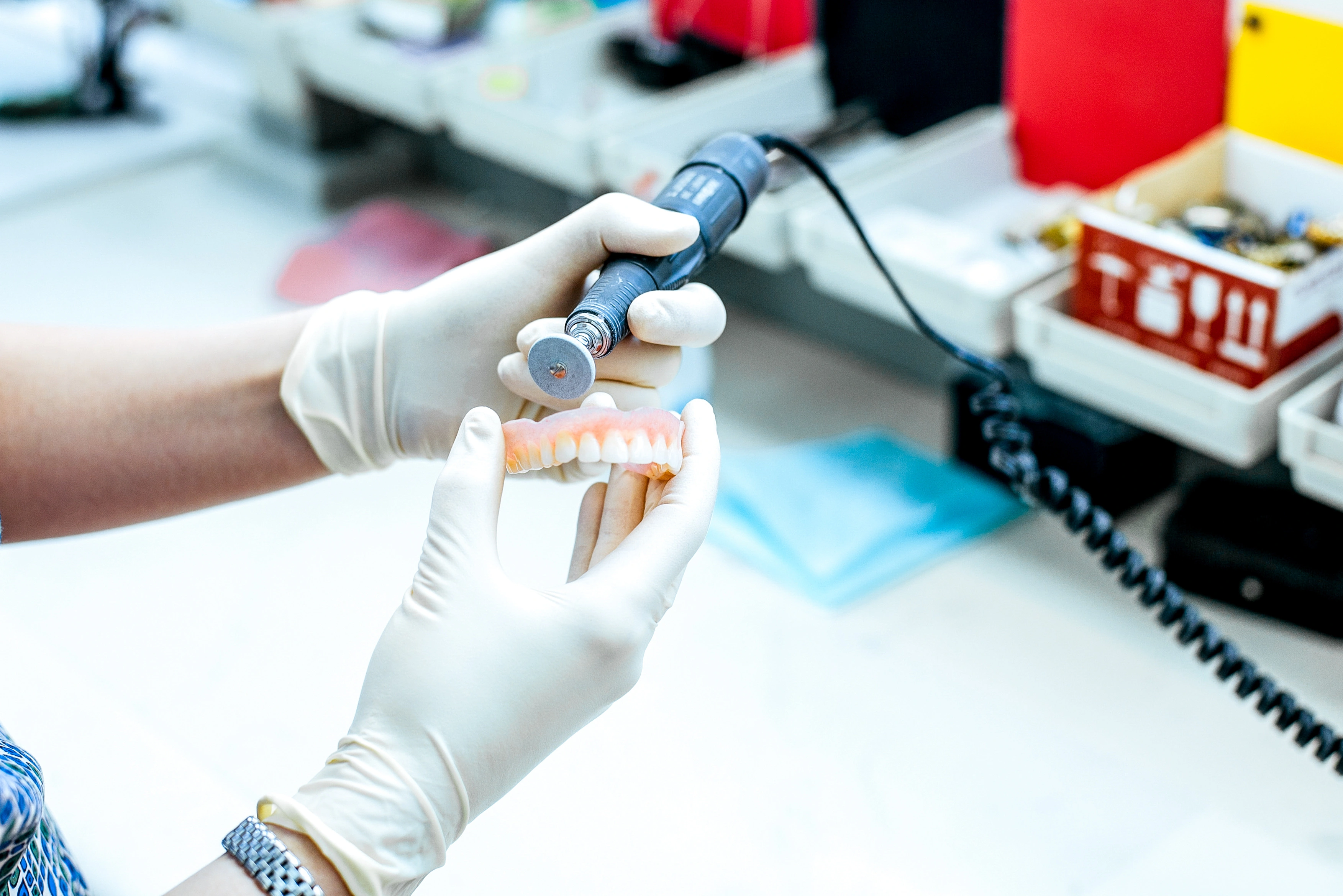 A dental technician uses a tool to make adjustments to a denture.